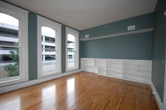 an empty living room with a wood floor and large windows