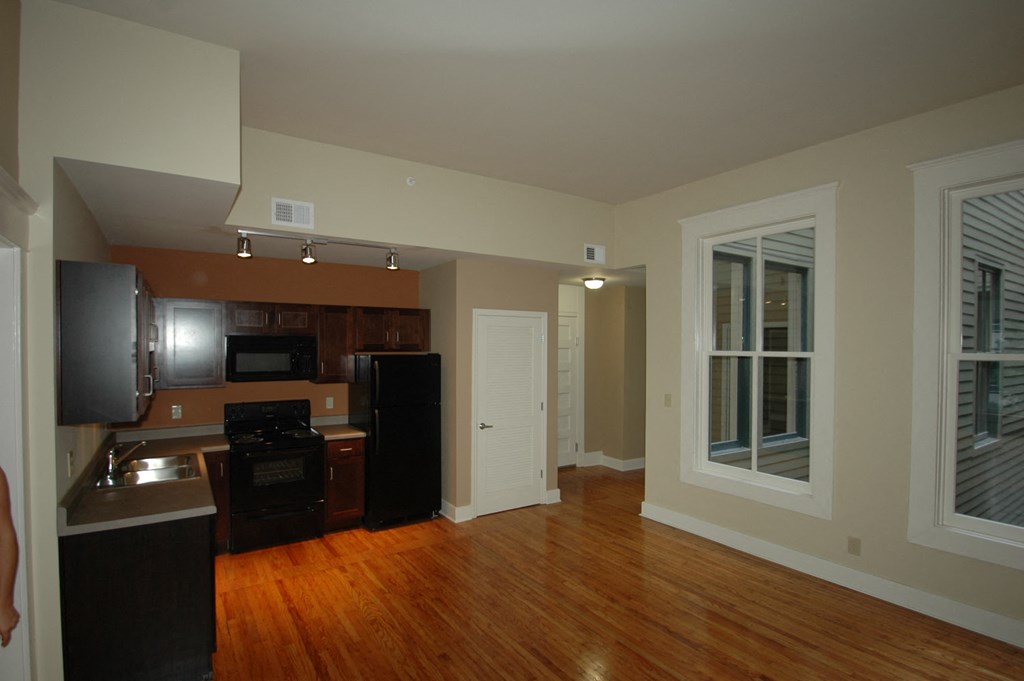 an empty kitchen and living room with wood floors