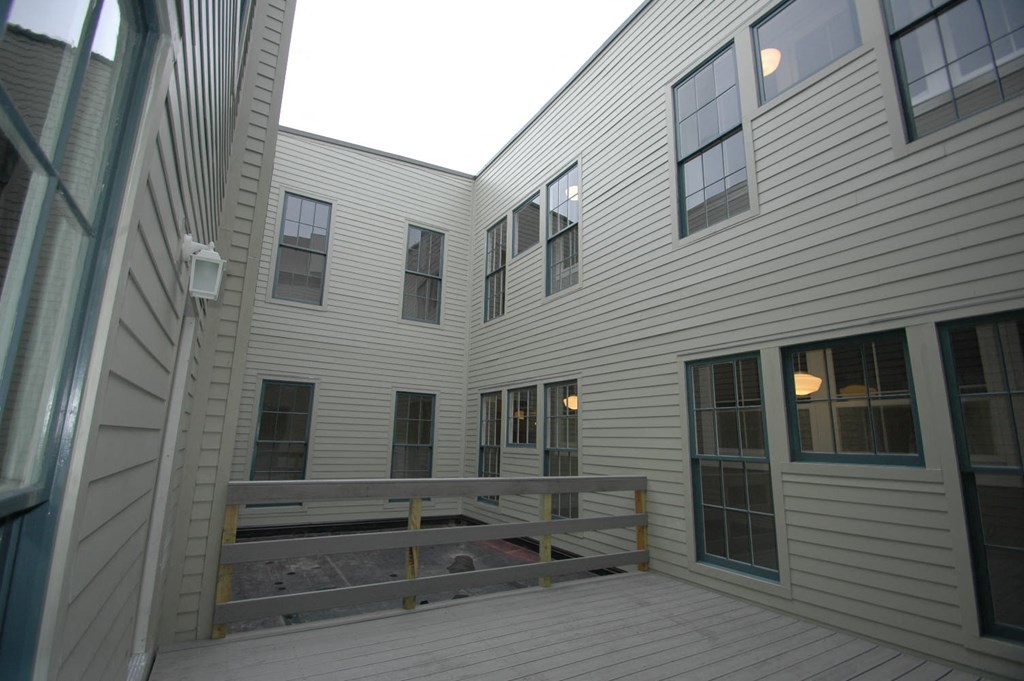 a view of the outside of a white house with a deck