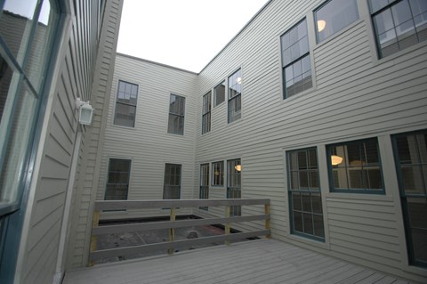 a view of the outside of a white house with a deck