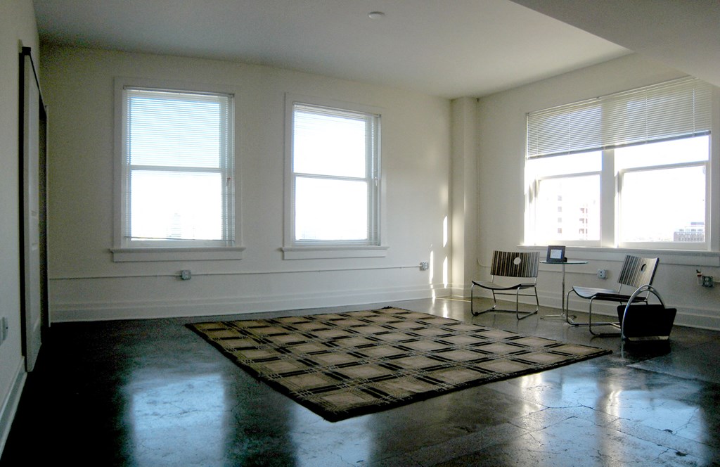 a living room with three windows and a rug