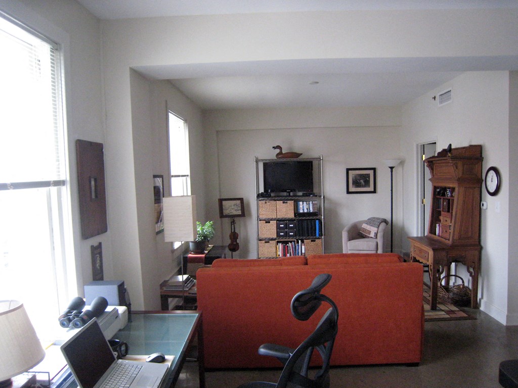 a living room with a orange couch and a desk