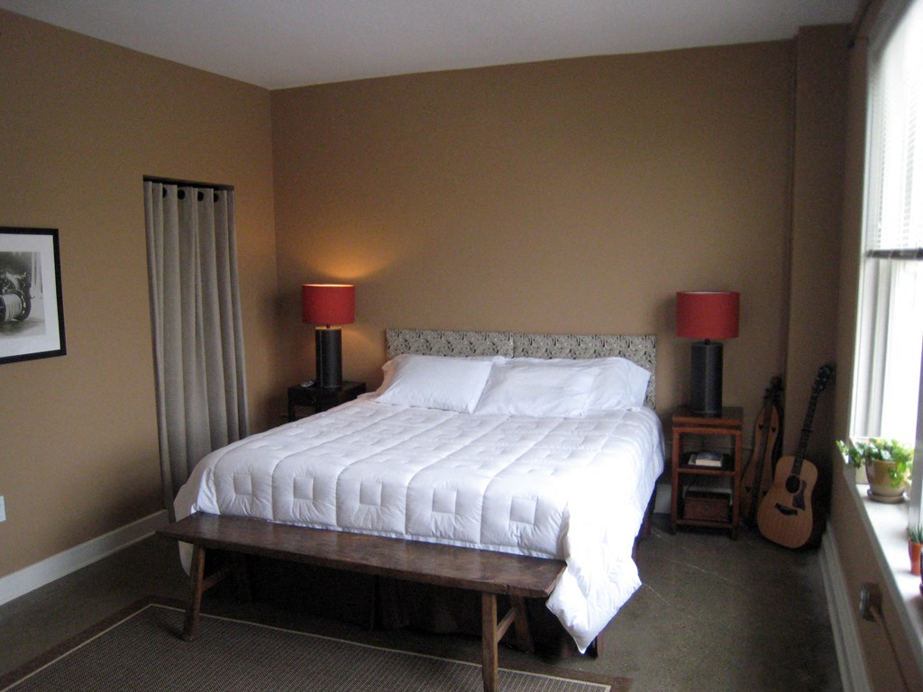 a bedroom with a large bed and a guitar on the wall