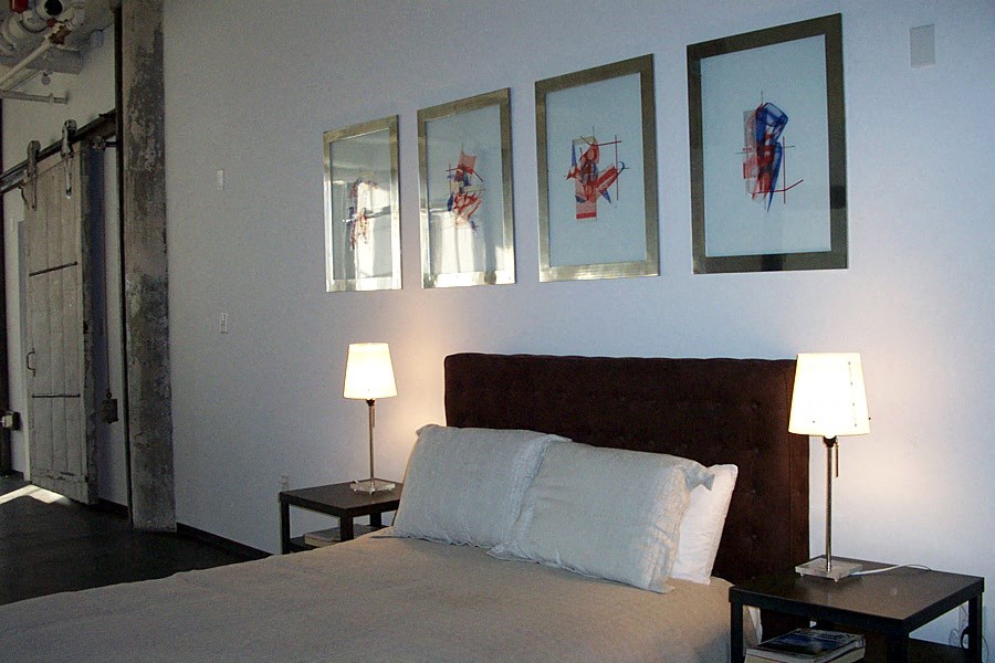 a bedroom with a bed and paintings on the wall