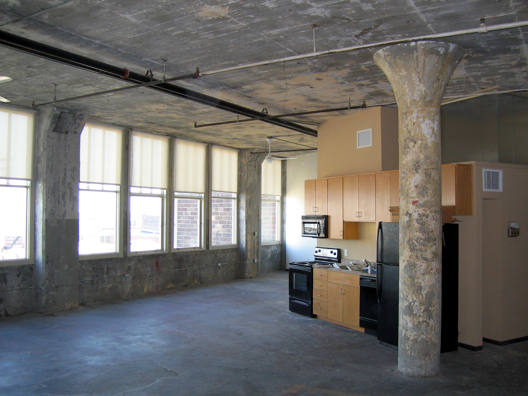 an empty living room with a kitchen and windows
