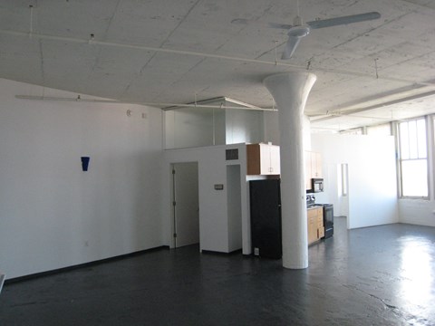 an empty office space with a ceiling fan and white walls
