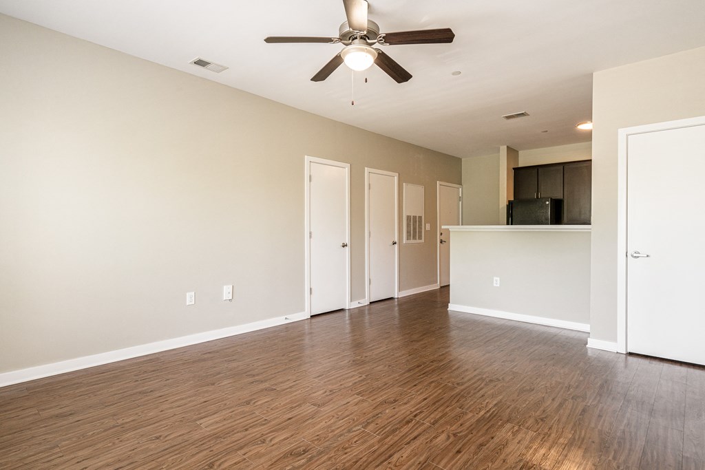 an empty living room with wood flooring and a ceiling fan
