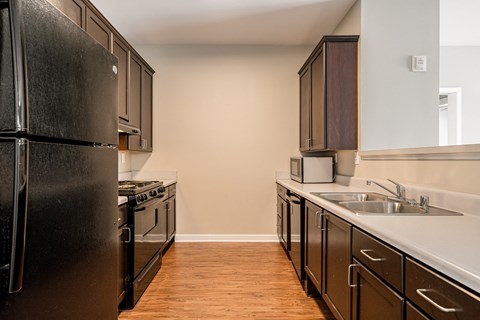 an empty kitchen with black appliances and wood flooring
