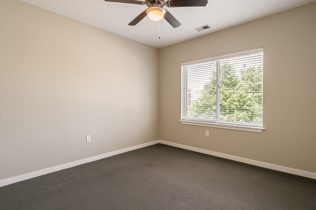 an empty room with a ceiling fan and a window