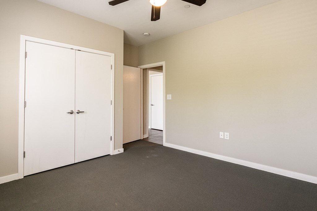 an empty room with white doors and a ceiling fan