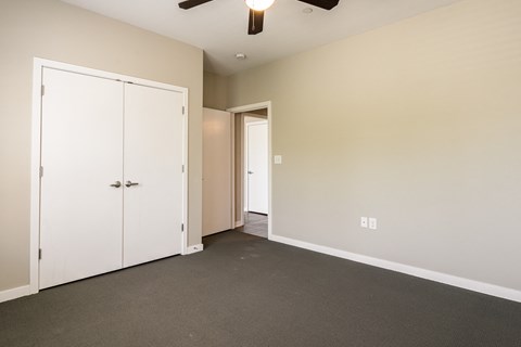 an empty room with white doors and a ceiling fan