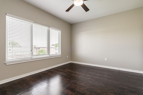 an empty living room with wood floors and a ceiling fan