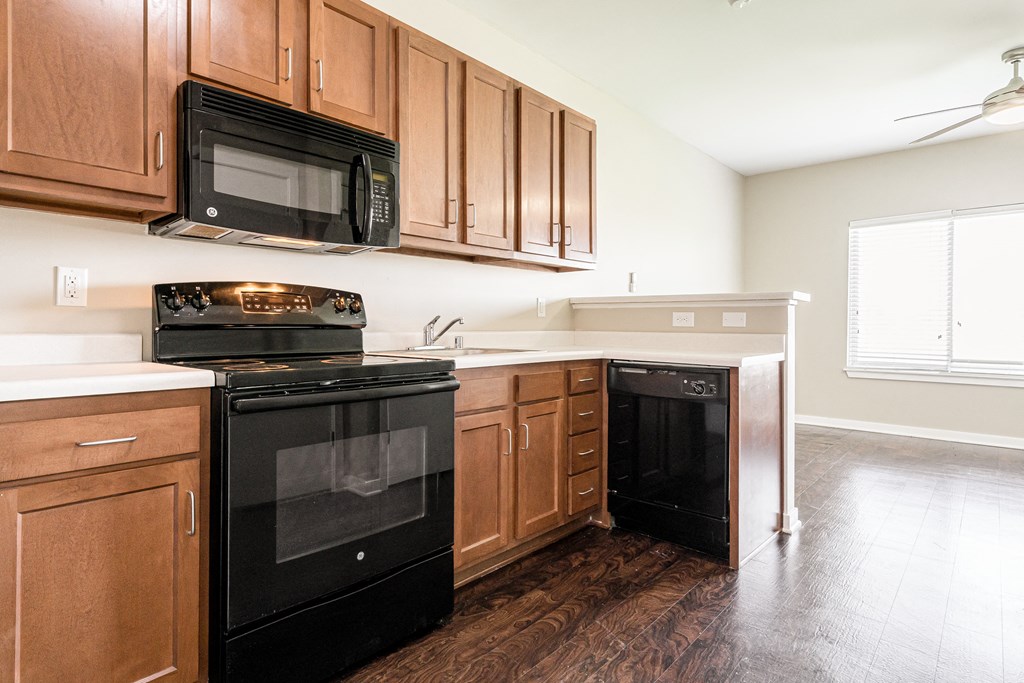an empty kitchen with black appliances and wooden cabinets