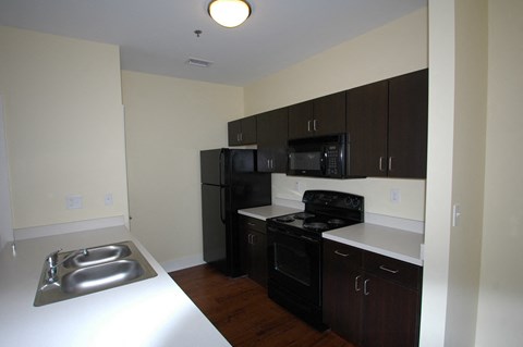a kitchen with black appliances and white countertops in an empty apartment