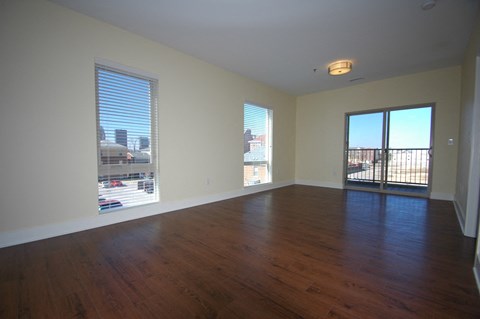 an empty living room with wood floors and a balcony