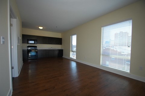 an empty living room and kitchen with wood floors and a large window