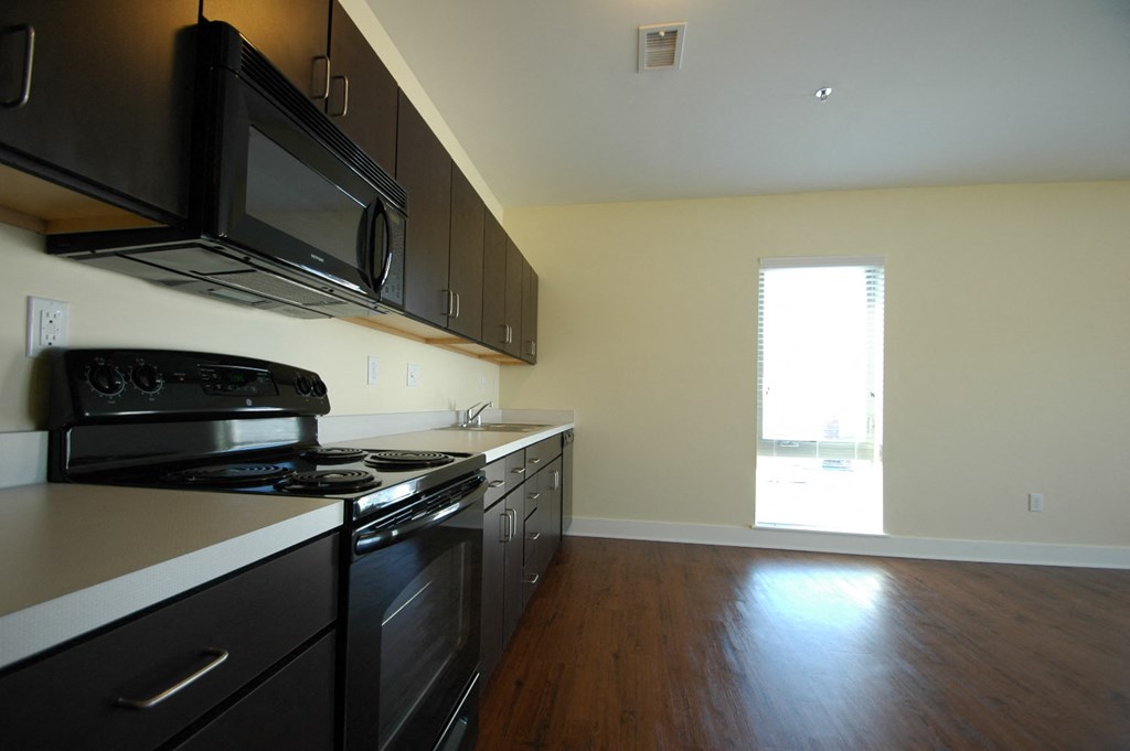 an empty kitchen with black appliances and a window