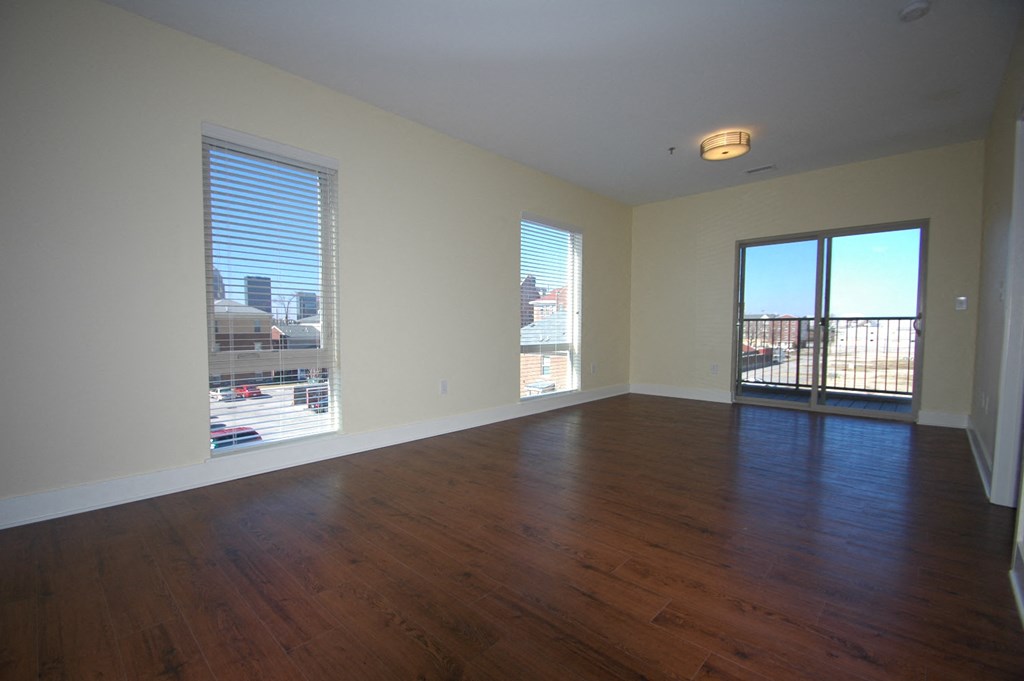 an empty living room with wood floors and a balcony