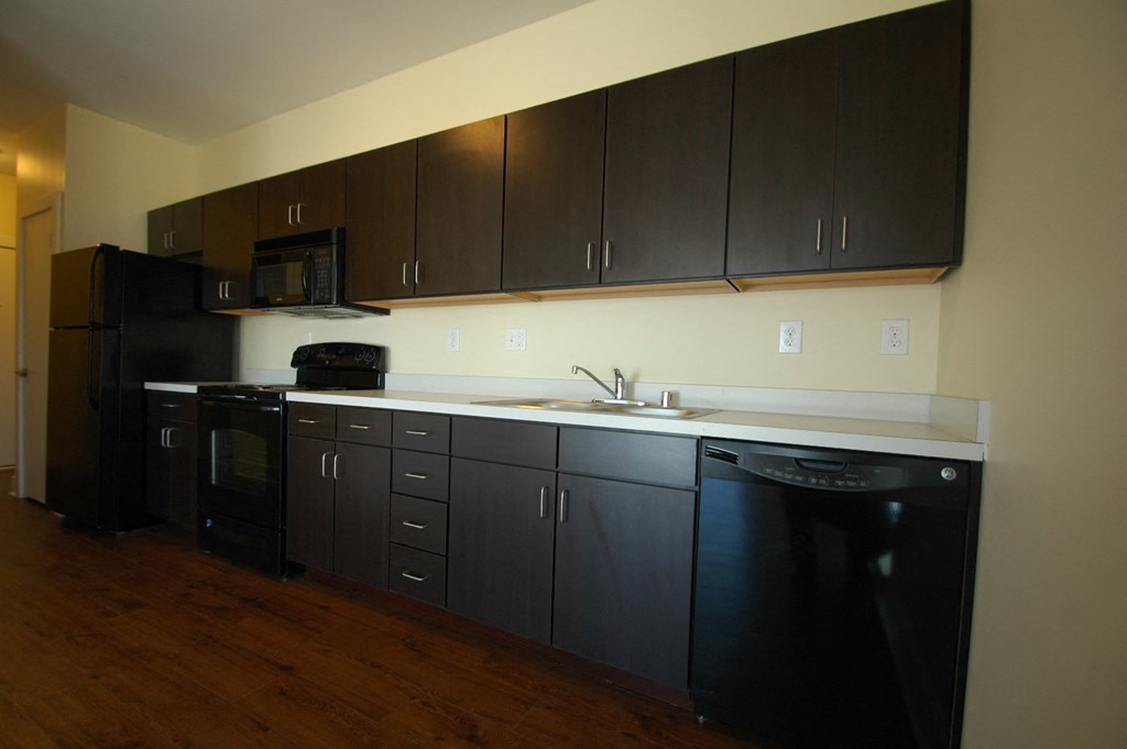 a kitchen with dark cabinets and a sink and a refrigerator