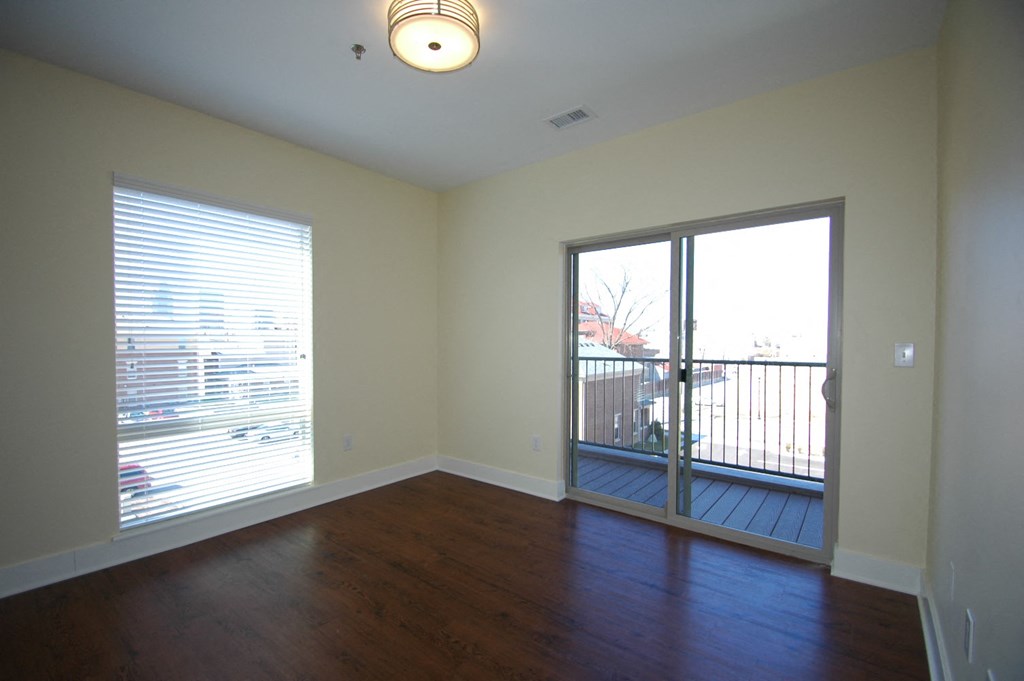 an empty living room with wood floors and a balcony