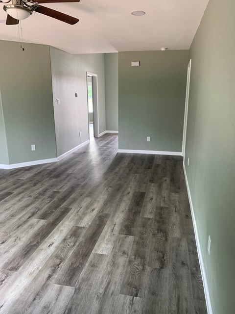 A room with a ceiling fan and wood flooring.