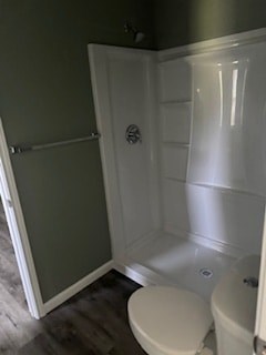 A white toilet sits in a bathroom next to a walk-in shower.