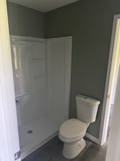 A white toilet in a bathroom with grey walls.