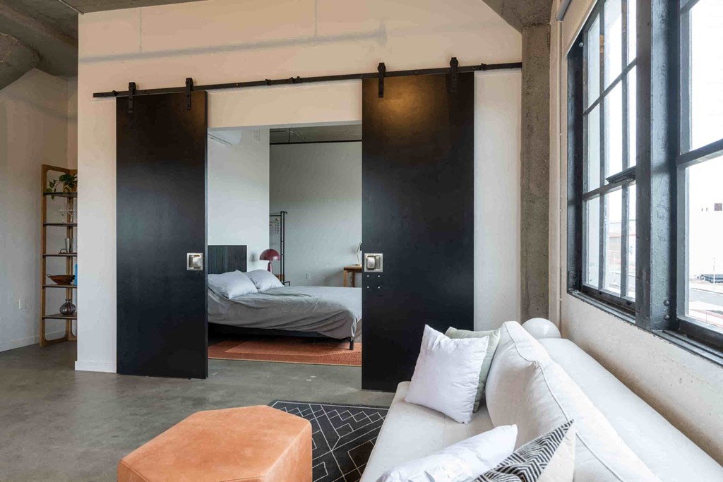 a living room with a couch and a sliding door to a bedroom