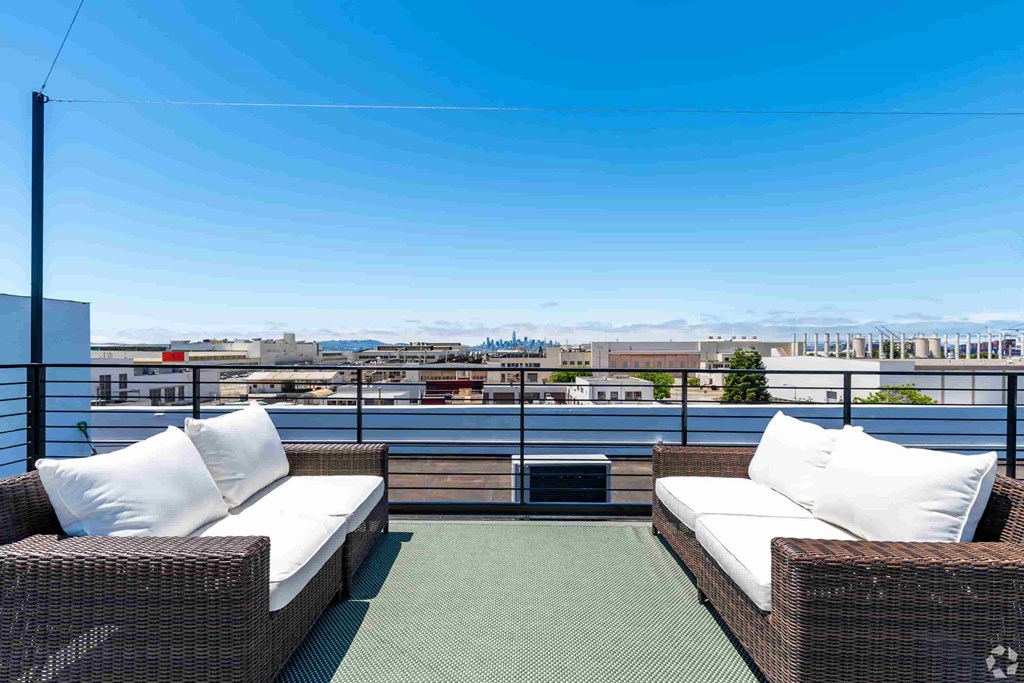 a balcony with two wicker chairs and a view of the water and the city