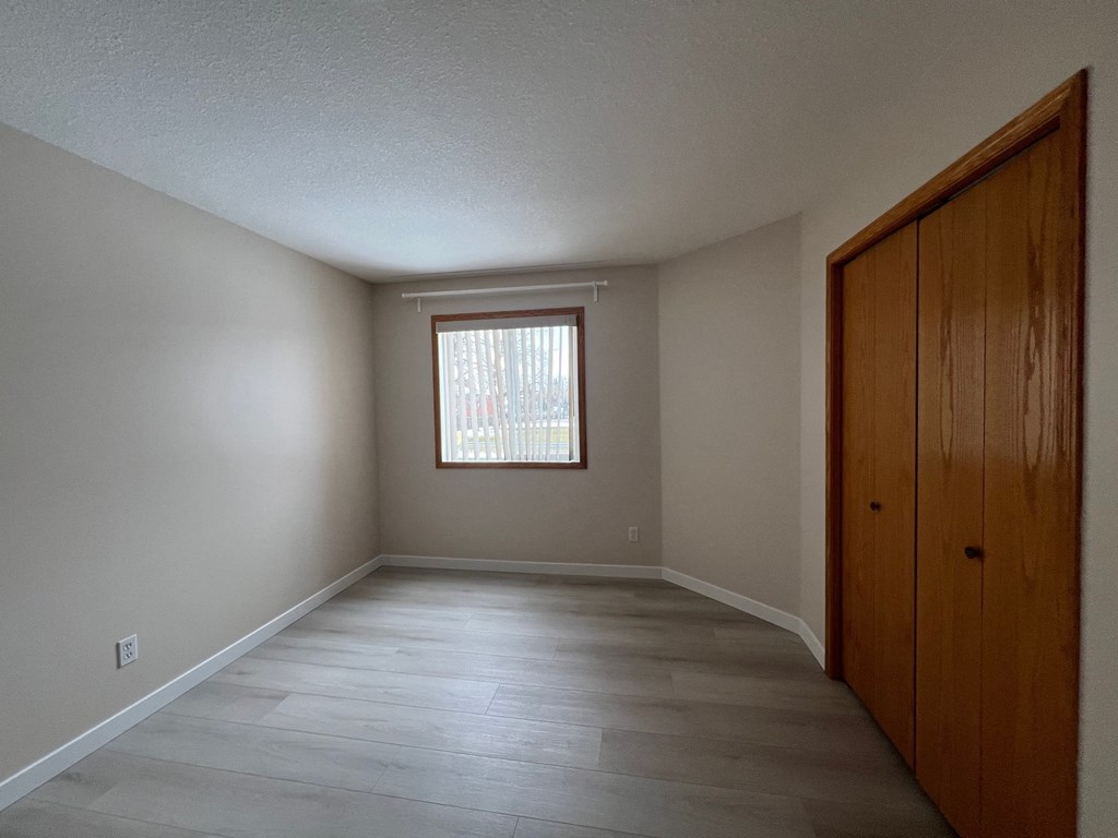 an empty living room with a window and wooden floors