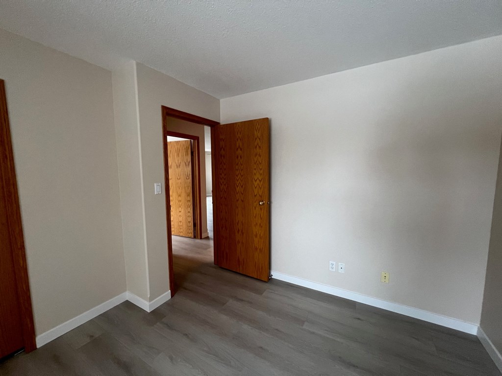 an empty living room with white walls and wood flooring