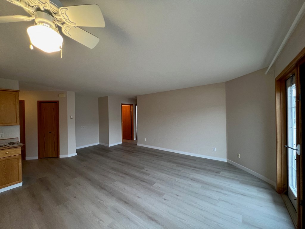 an empty living room with wooden floors and a ceiling fan