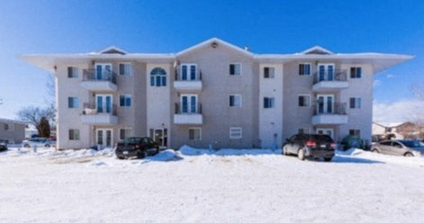 an apartment building with cars parked in the snow
