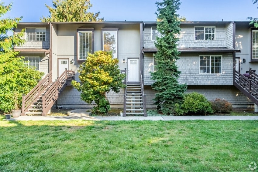 the front of an apartment building with green grass and a sidewalk
