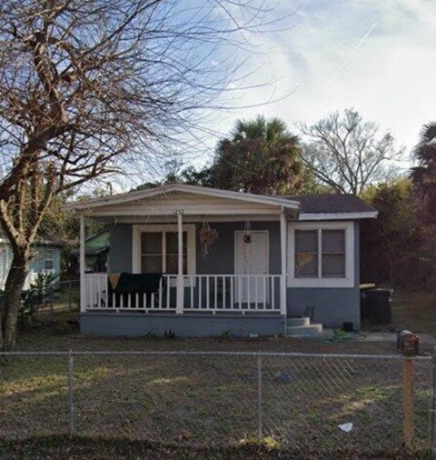a small blue house with a porch and a fence