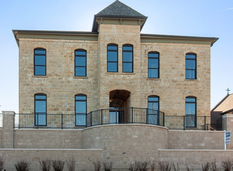 A large stone building with a black iron fence in front.