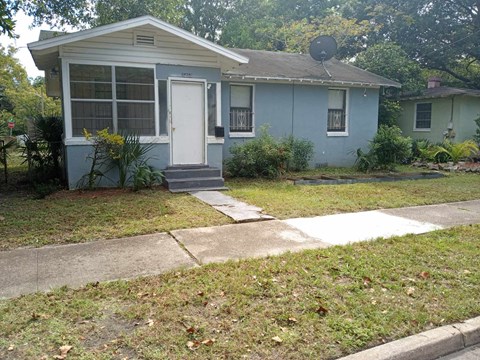 a blue house with a sidewalk in front of it