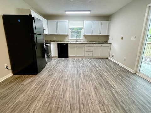 A kitchen with black appliances and white cabinets.