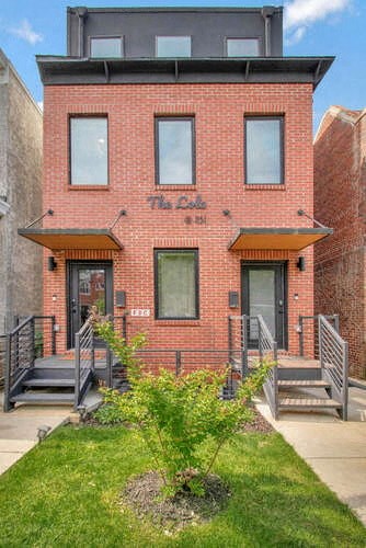 the front of a brick building with a yard and stairs