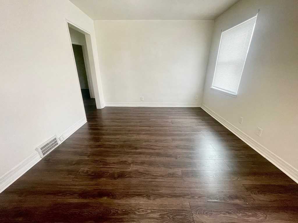 an empty room with wood floors and white walls