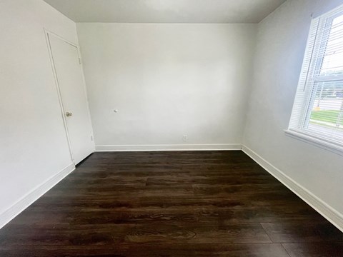 an empty room with wood floors and white walls