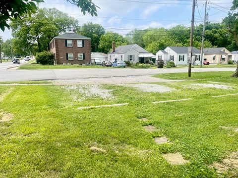 a neighborhood with houses and a street with grass and dirt