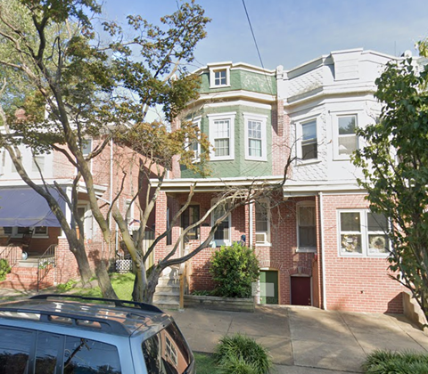 A house with a green roof and a tree in front.