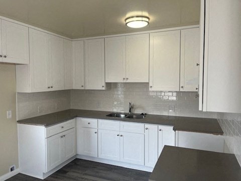 an empty kitchen with white cabinets and a sink