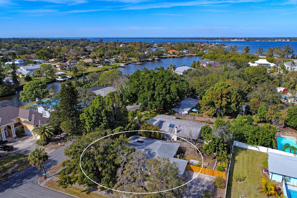 an aerial view of a house with a body of water in the background