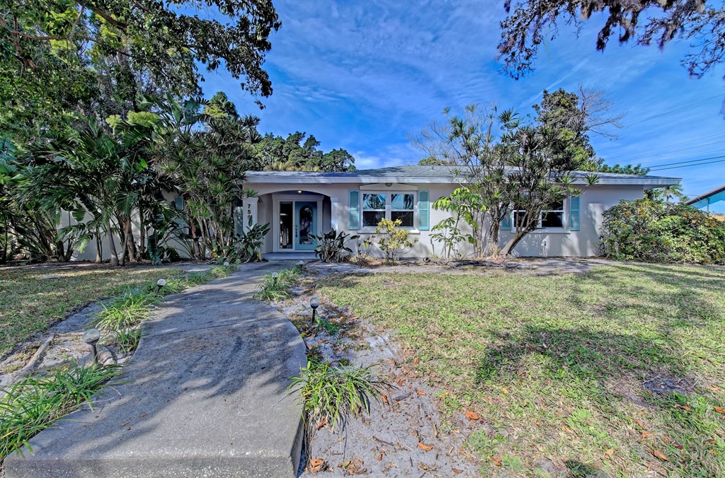 a white house with a driveway and a lawn and trees