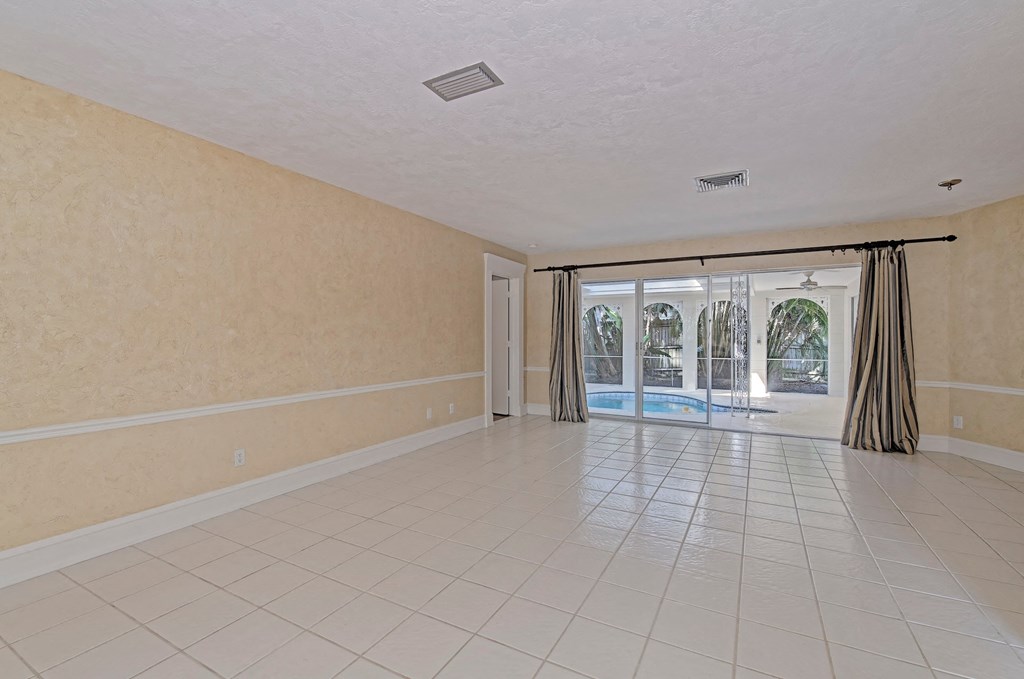 an empty living room with a sliding glass door to a pool