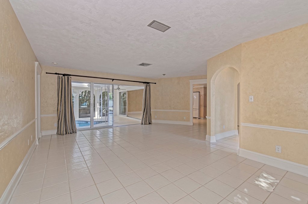 an empty living room with a tile floor and a sliding glass door