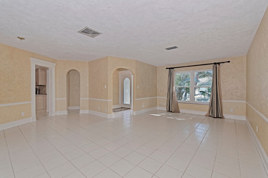 an empty living room with a tile floor and a window