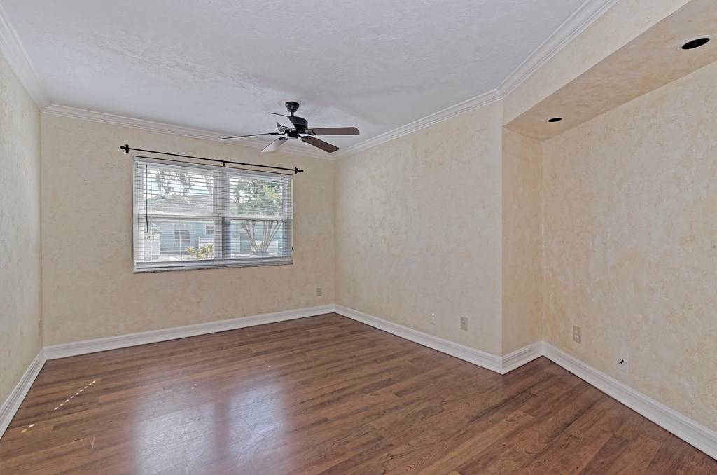 an empty living room with a ceiling fan and a window